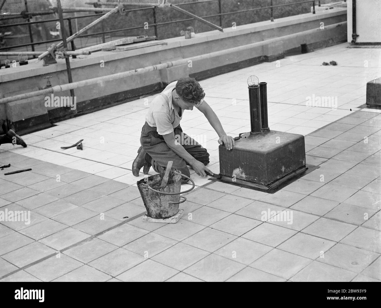 Workers from Val De Travers Asphalt Limited , a paving company , working on paving the roof of the London Jewish Hospital in Stepney Green . 1938 Stock Photo