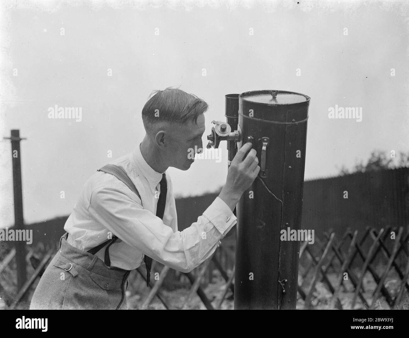 Dr Hugh Percival Wilkins PhD FRAS 1896 - 1960 was a British engineer by profession but most notably known as an amateur astronomer and particularly as a moon mapper . In his life he has created a number of moon maps , doing much of the observing from his home . Photo shows Mr Hugh Percy Wilkins at work , looking through a telescope , in the garden of his home in Barnehurst , Kent . 1938 Stock Photo