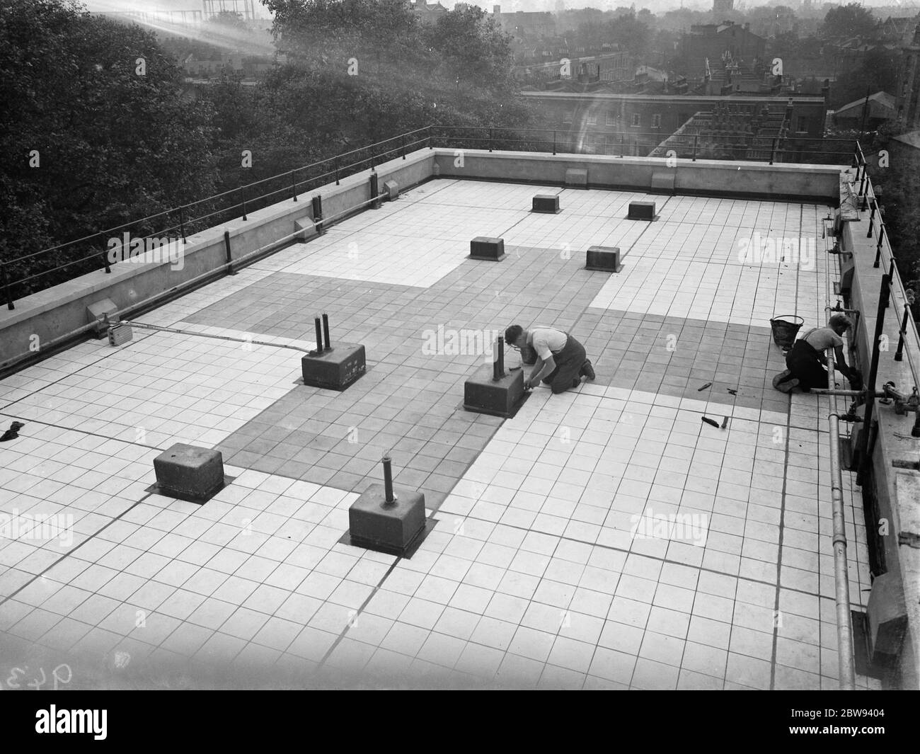 Workers from Val De Travers Asphalt Limited , a paving company , working on paving the roof of the London Jewish Hospital in Stepney Green . 1938 Stock Photo