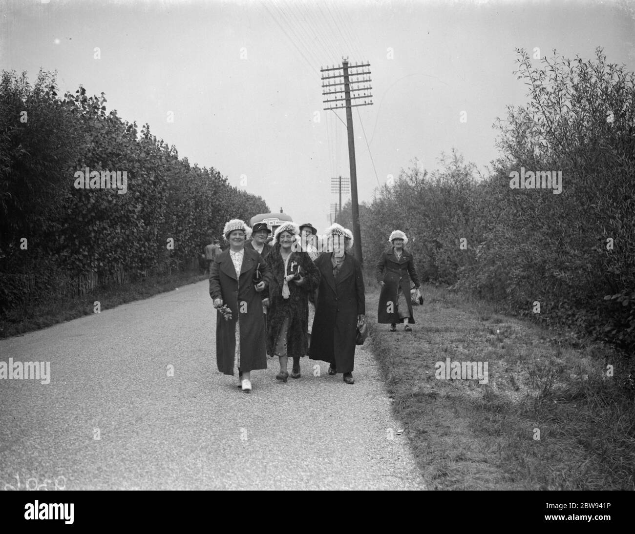 Hop pickers walk along a country lane . 1935 . Stock Photo