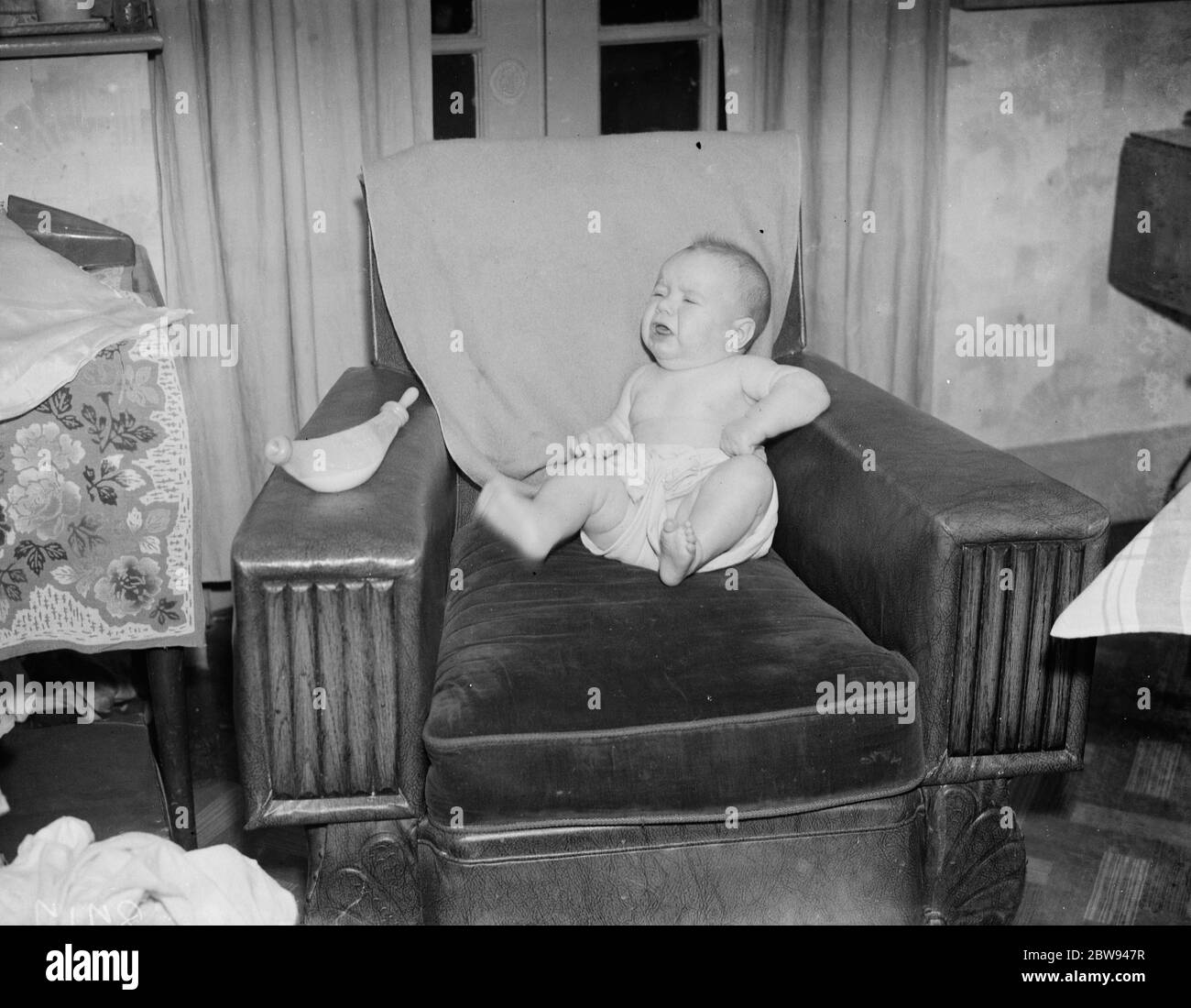 A baby crying in an armchair . 1938 Stock Photo