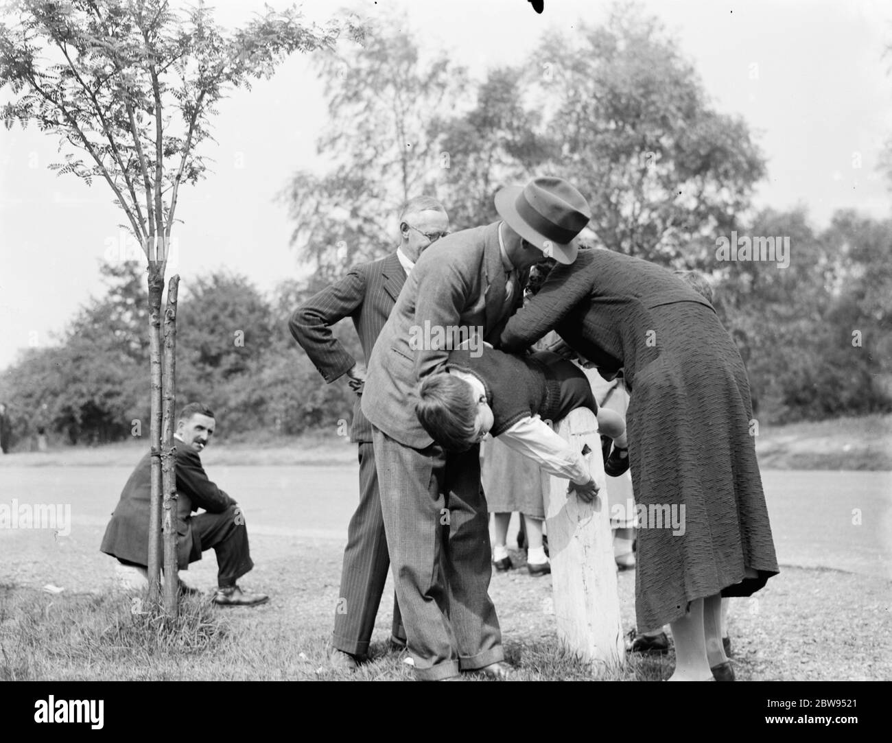 ' A stitch in time saves nine '. A mother sewing up a small hole on her boys trousers . 1936 Stock Photo