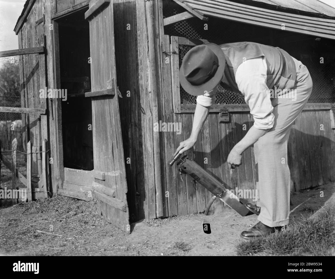 A man giving a cyanogas demonstration . He pumps the gas into the rat borrow . 1936 Stock Photo