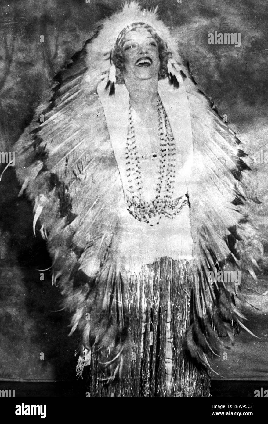 America 's Night Club Queen dons feathers . Texas Guinan , the famous night club Queen of America who has been continually in trouble with the police for some time , in full Indian feathers and in merry mood at the Beaux Arts Ball in New York . 6 February 1932 Stock Photo