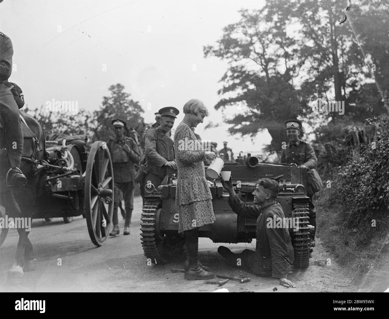 Refreshments on the Surrey front . Receiving a welcome drink from a cottager during repairs to their armoured vehicle , during British Army manoeuvres on the Surrey front . 16 August 1932 Stock Photo