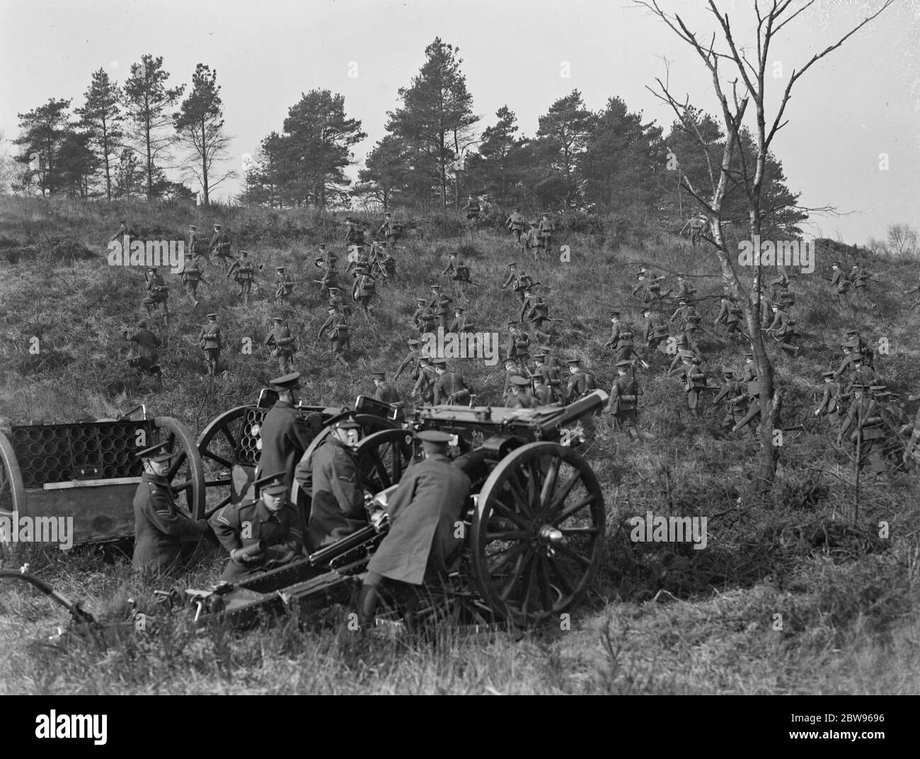 Harrow school cadets hold field day at Aldershot . Harrow school officers training corps had the annual field day , carrying out operations in the Long Valley at Aldershots . Harrow cadets retreating while the Royal Artillery hold gun practice in the Long Valley . 1 March 1932 Stock Photo