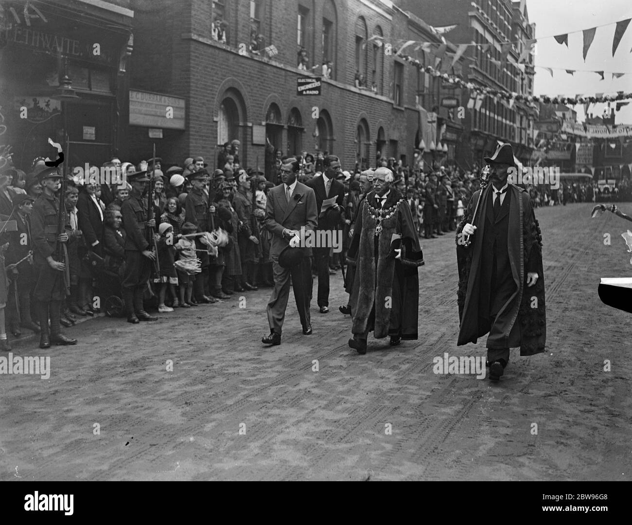 Prince George receives great welcome in Clapham . Prince George received a warm welcome when he visited Clapham , London , S W to open the new baths in Manor Road . The Prince George and Col B Bellamy , Mayor of Wandsworth walking down the street . 7 July 1932 Stock Photo