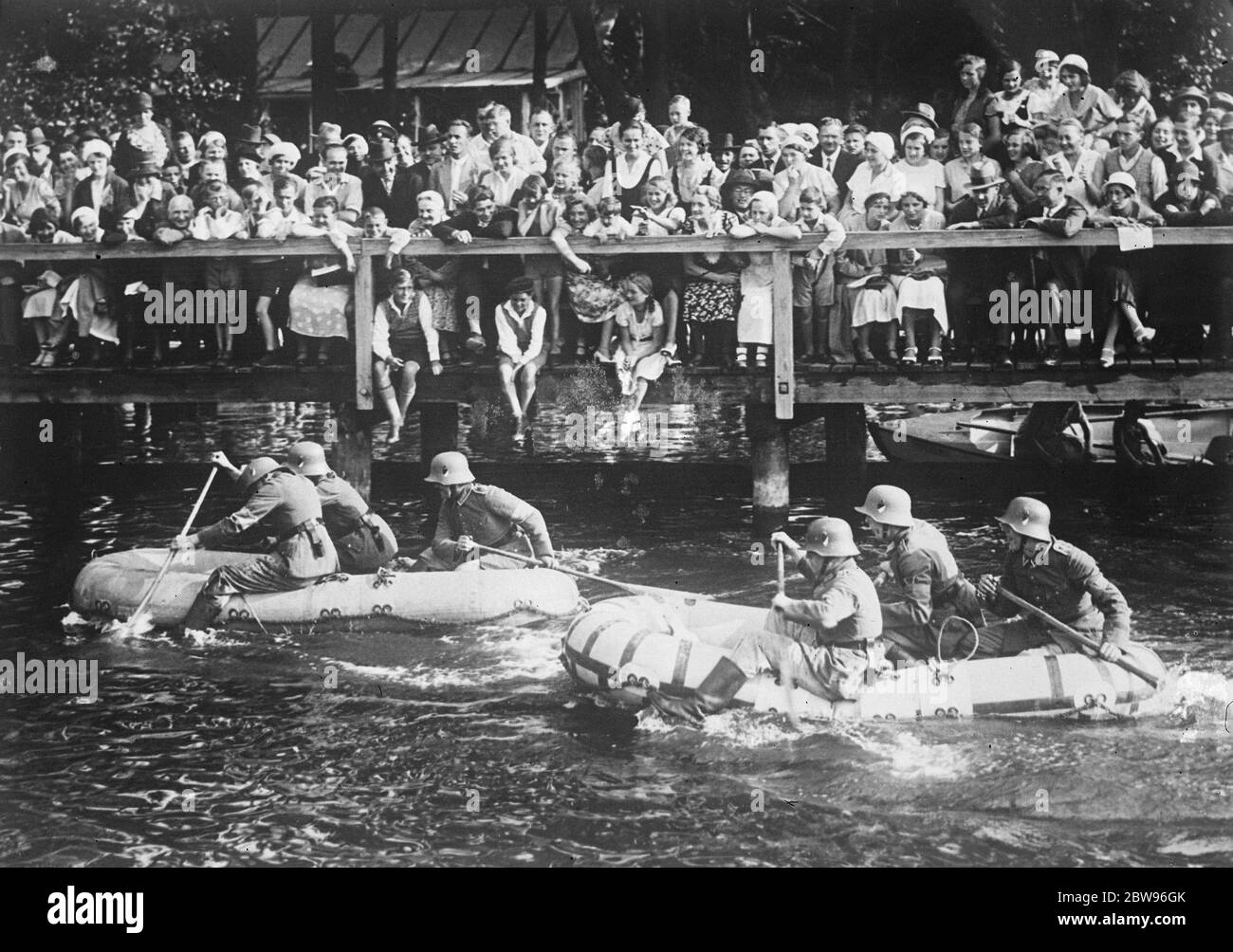 German army holds military water festival . Great crowds gathered at Spandau , Germany , to see the water festival of the 9th infantry regiment of the German army . There were many original events . A race between rubber pontoon boats piloted by soldiers during the festival . 2 August 1932 Stock Photo