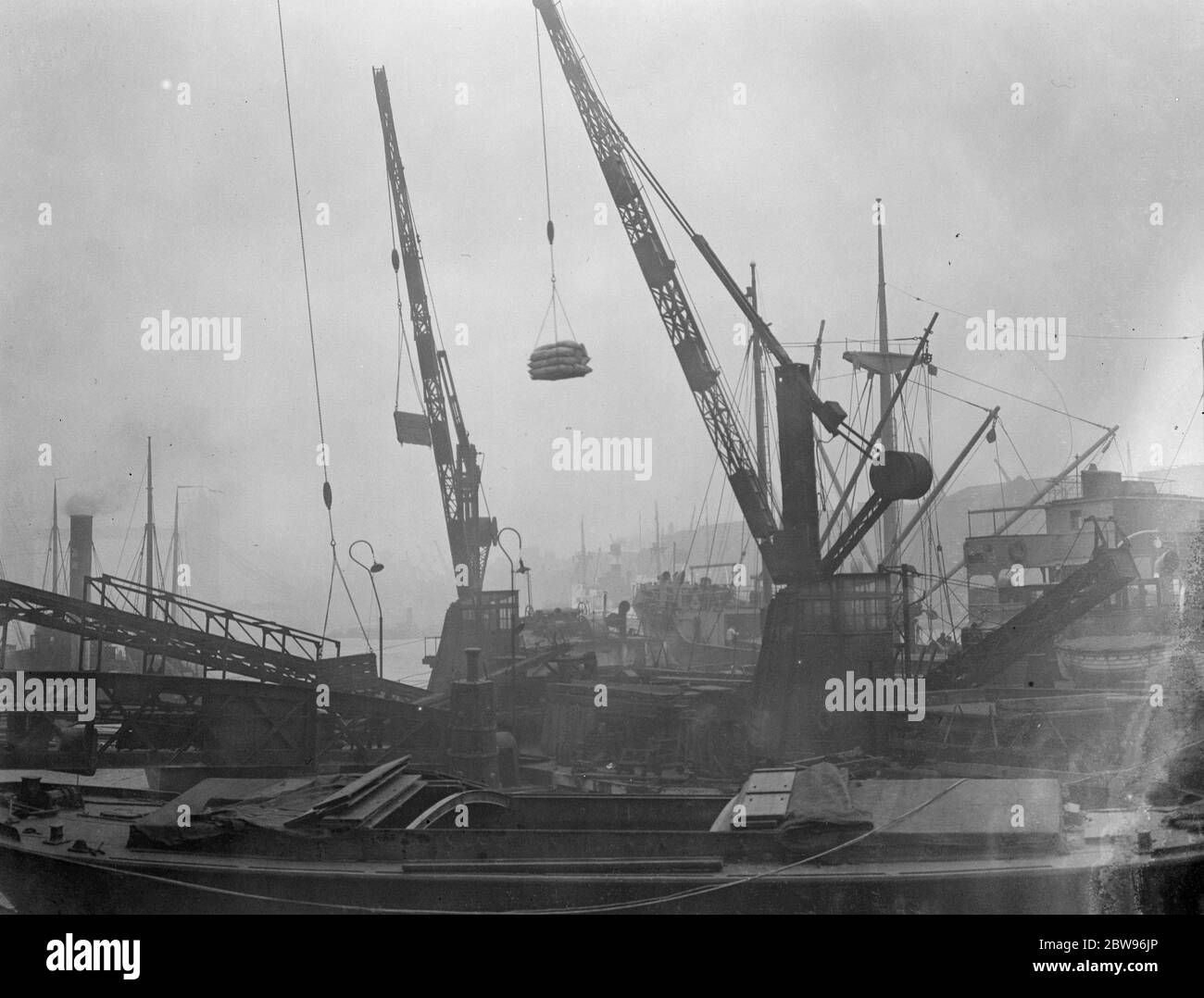 Last minute rush to land foreign goods continues in the London docks . Thousands of dock partners are engaged in a last minute rush to unload more than two hundred ships which have arrived in the Thames to land their cargoes before the implication of the 10 percent duty which comes into force tomorrow . A barge heavily laden with foreign goods unloaded in the early hours of the morning at the London docks . 29 February 1932 Stock Photo