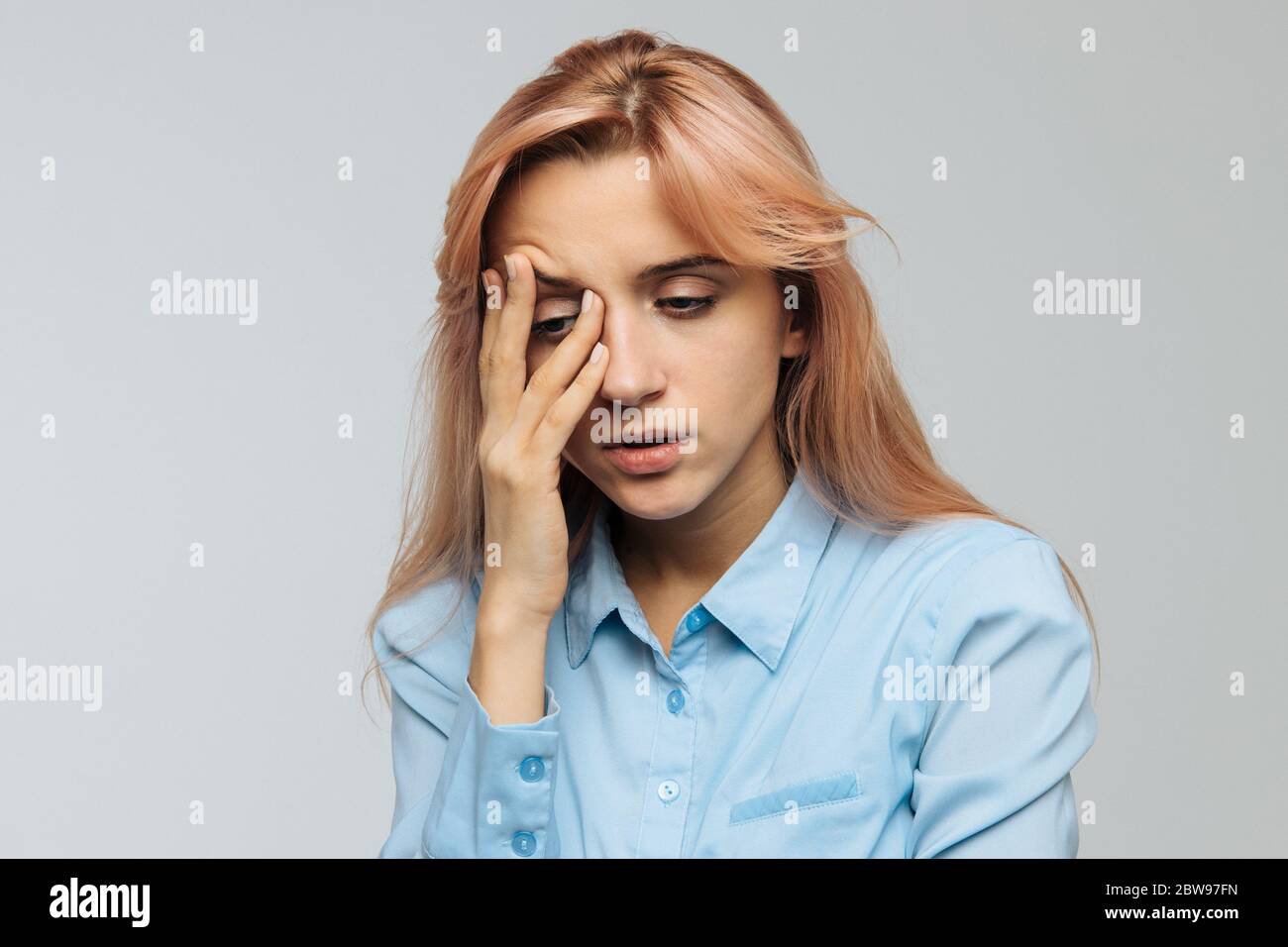 Displeased woman nearly falling asleep at work, hold her head with hand.Sleepy student spending time in university, feels lack of energy. Sleep depriv Stock Photo