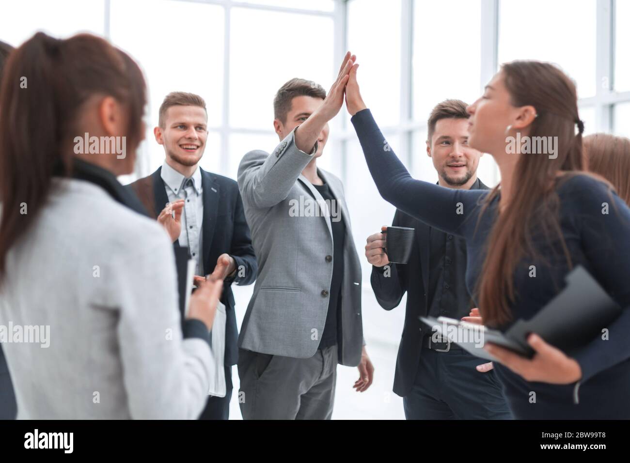 young employees giving each other a high five Stock Photo - Alamy
