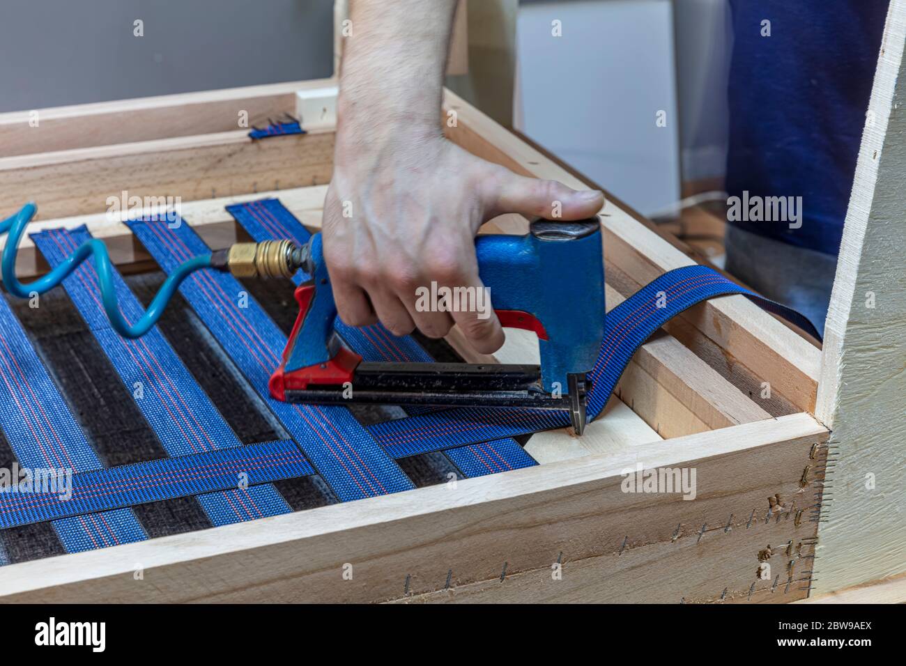 Manufacture of Furniture Seats. Professional male carpenter upholstering vintage armchair in