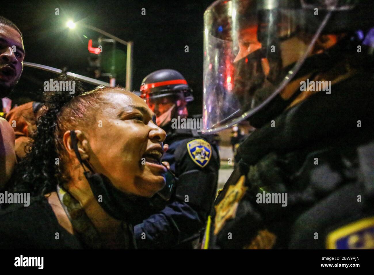 A protester yells at a police officer inches away during the demonstration. A peaceful protest, spurred by the death of George Floyd, turned violent as protesters clashed with police, throwing rocks and bottles at police while police responded by shooting pepper spray balls at protesters and using flash bang grenades to disperse the crowd. Stock Photo