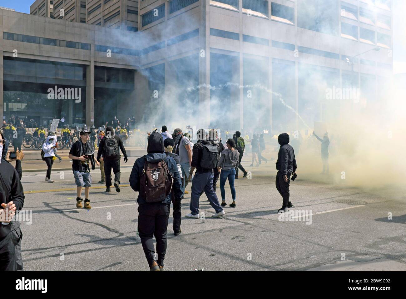 Police and demonstrators square off in front of the Justice Center in downtown Cleveland, Ohio, USA during protests of police brutality. Tear gas canisters volley between the police and demonstrators along Lakeside Avenue. Stock Photo