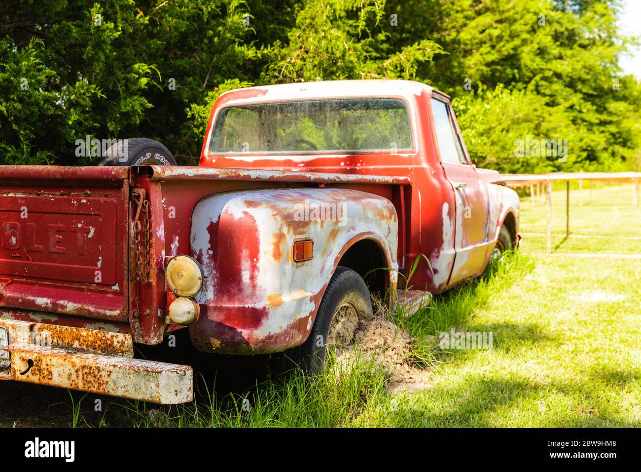 Abandoned Antique red truck parked in a field on a farm Stock Photo