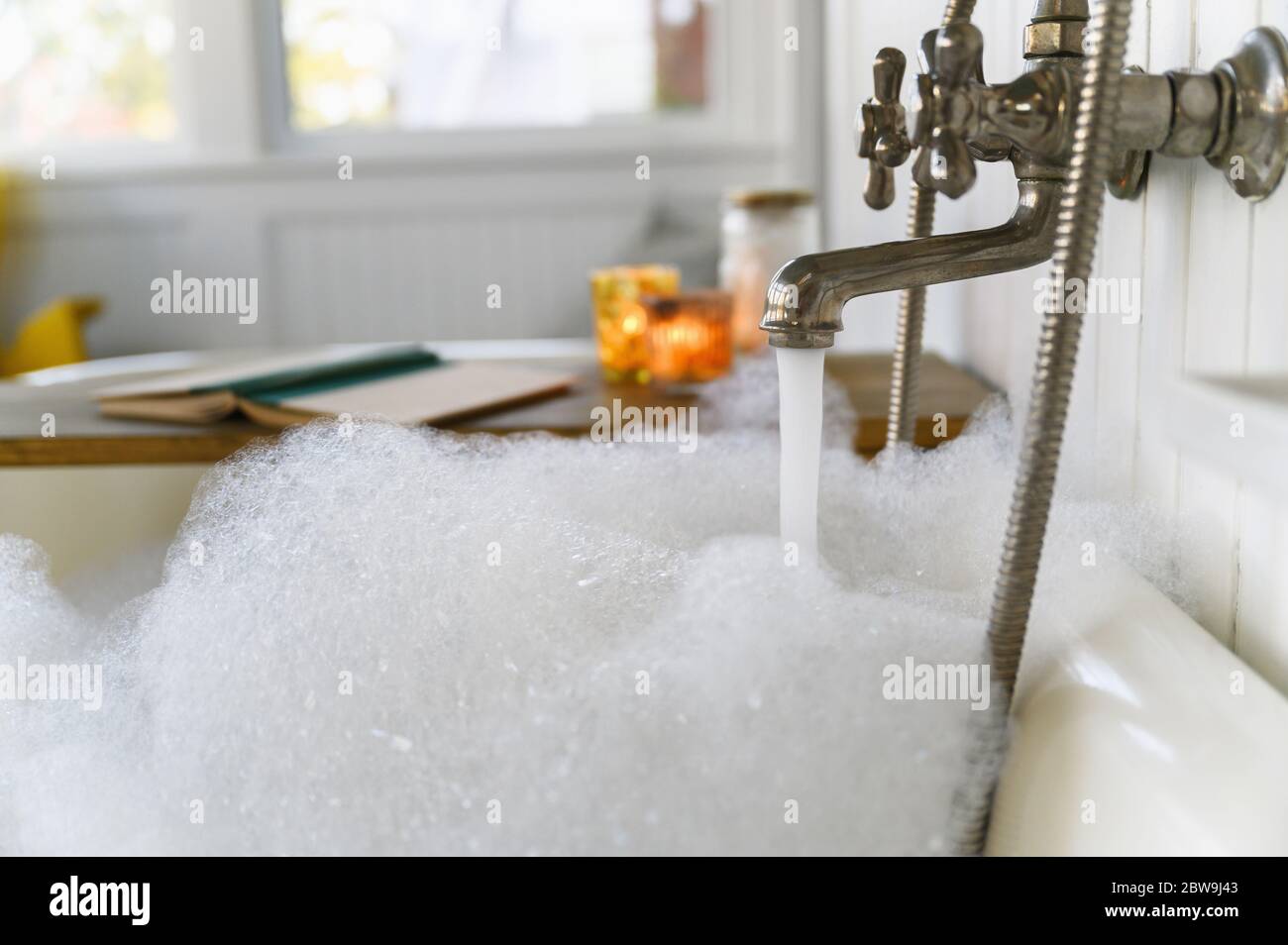 Bubble bath with book and candles Stock Photo