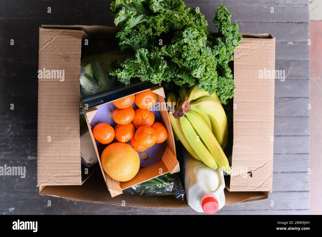 Overhead view of box of delivered produce on house porch Stock Photo