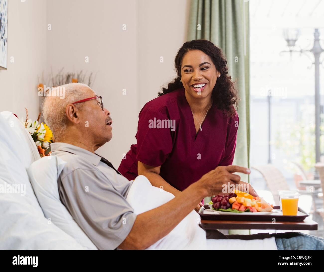Nurse bringing healthy meal to senior man in bed Stock Photo