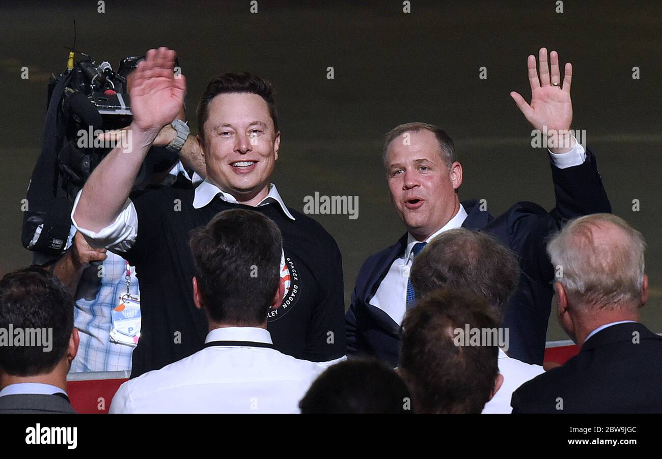 SpaceX CEO Elon Musk (left) and NASA Administrator Jim Bridenstine wave to the audience after the successful launch of a Falcon 9 rocket with the Crew Dragon spacecraft from pad 39A at the Kennedy Space Center during a post launch event at NASA's Vehicle Assembly Building with U.S. President Donald Trump and Vice President Mike Pence. NASA astronauts Doug Hurley and Bob Behnken will rendezvous and dock with the International Space Station, becoming the first people to launch into space from American soil since the end of the Space Shuttle program in 2011. Stock Photo