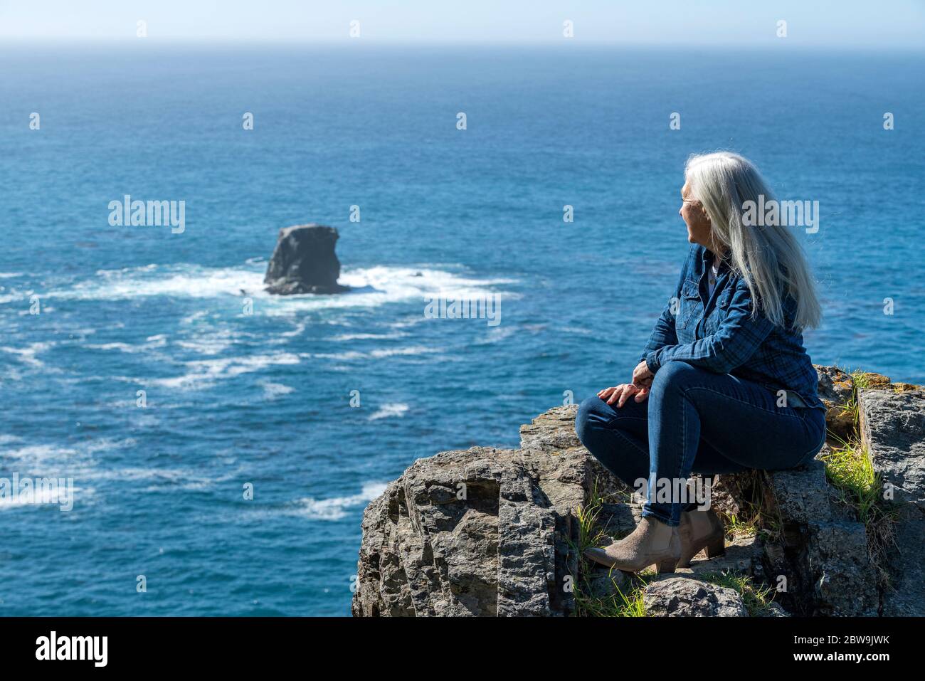 USA, California, Big Sur, Woman sitting at the edge of cliff looking at view Stock Photo