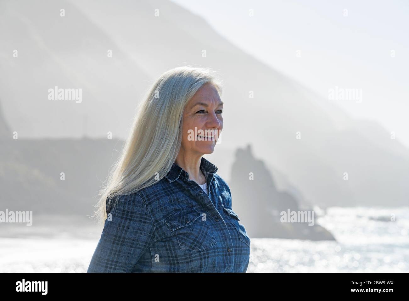 USA, California, Big Sur, Portrait of senior woman in front of cliffs Stock Photo