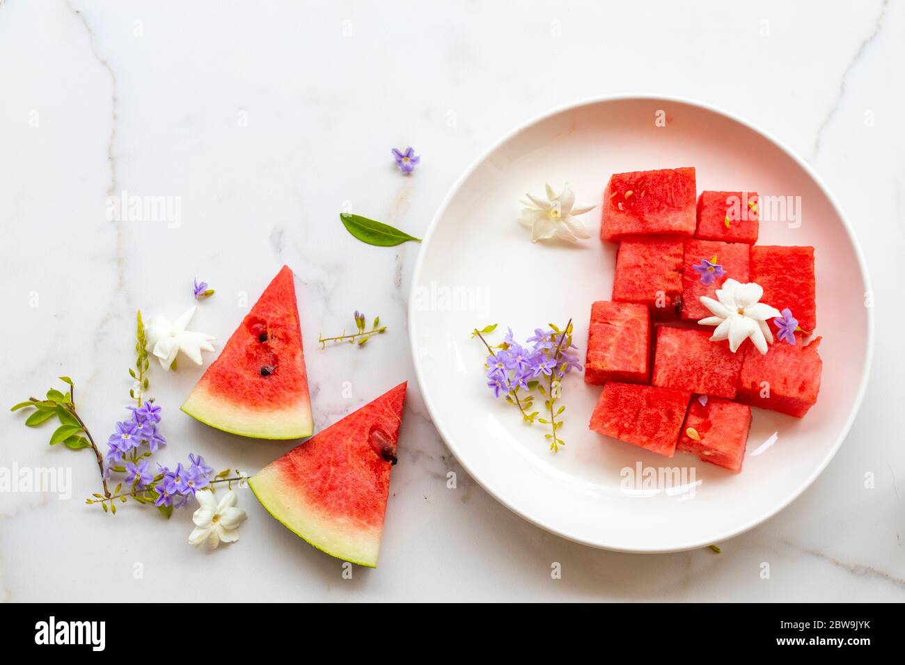 colorful fresh fruits watermelon healthy foods for health care with purple flowers ,jasmine in dish of lifestyle in summer season on white flagstone Stock Photo