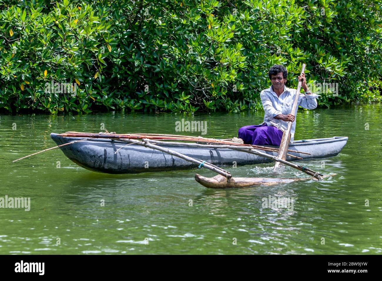 A man paddles an outrigger canoe along the Madu River at Balapitiya in