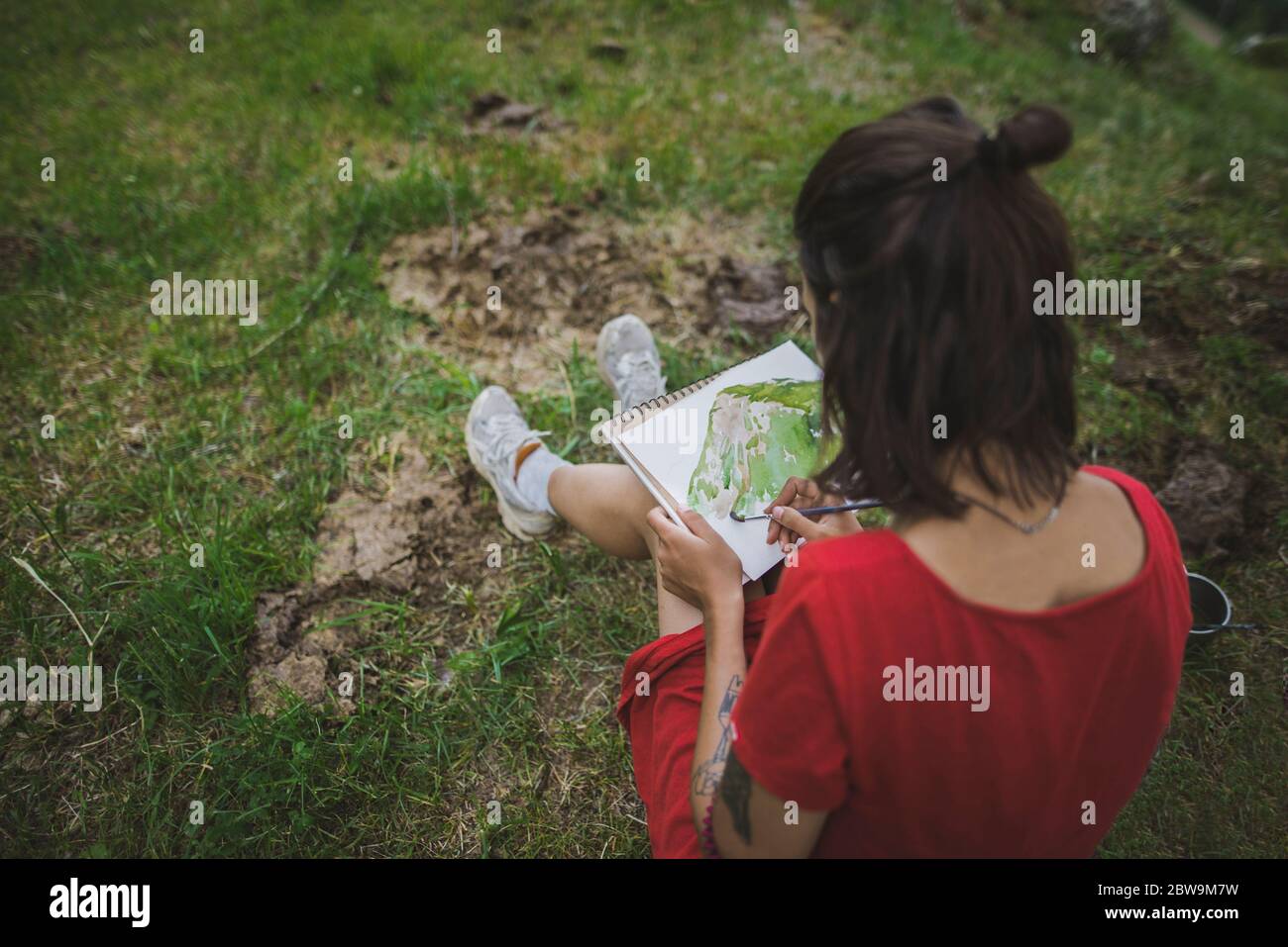 Switzerland, Obergoms, Young woman painting withÂ watercolorÂ in Swiss Alps Stock Photo