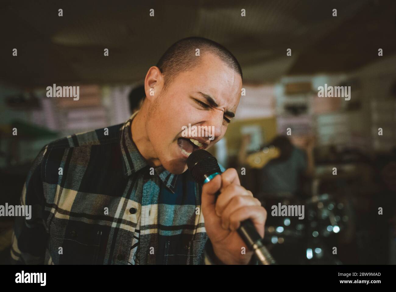 Young man singing during rehearsal in garage Stock Photo