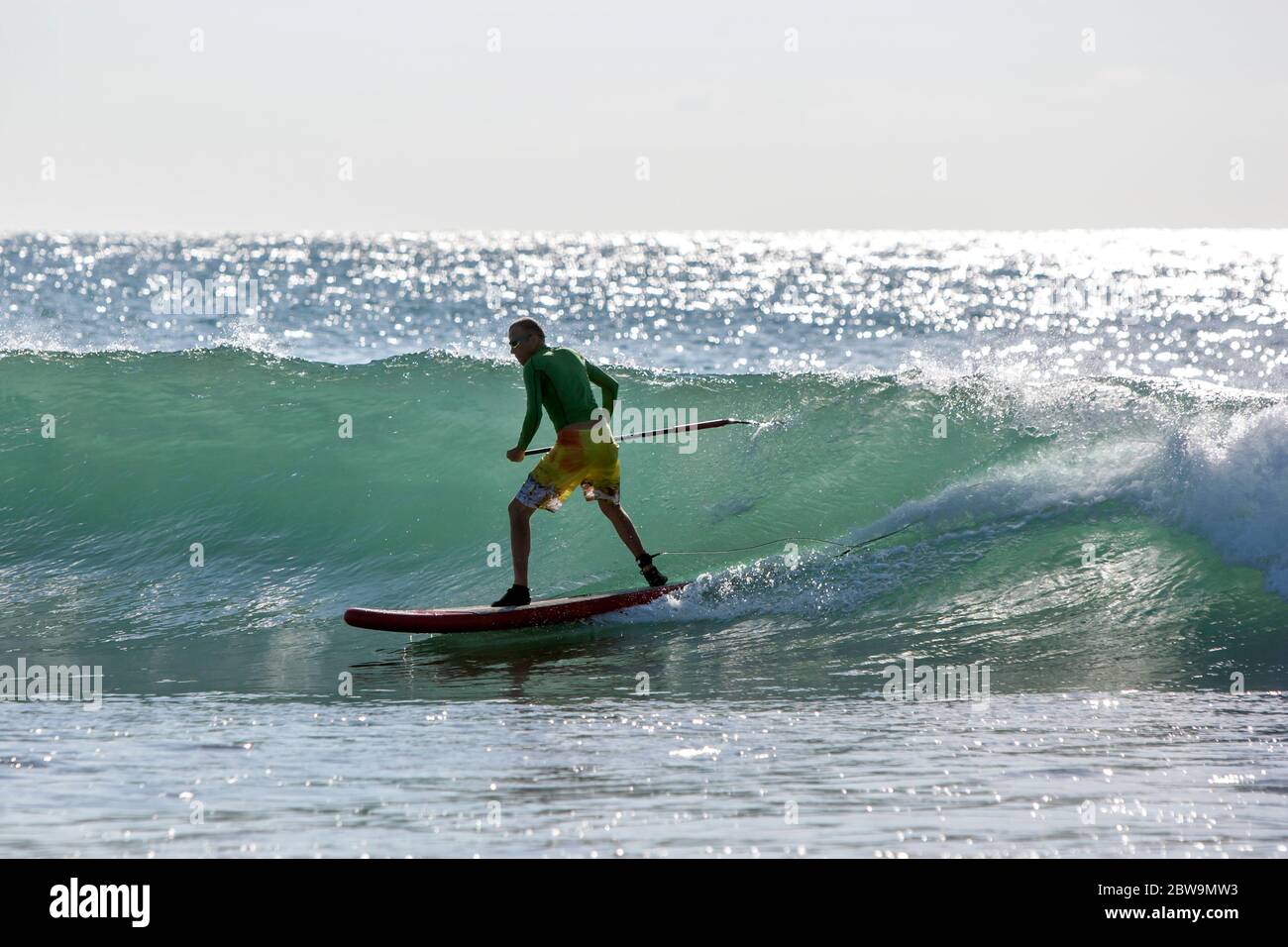 A stand up surfer rides a point break wave at Arugam Bay in Sri Lanka in the early morning. Stock Photo