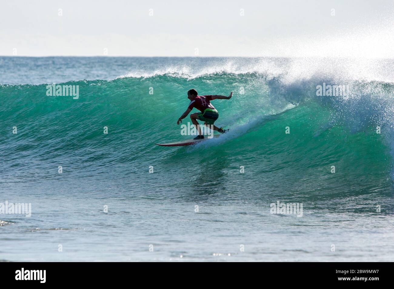 A surfer rides a point break wave at Arugam Bay in Sri Lanka in the early morning. Stock Photo