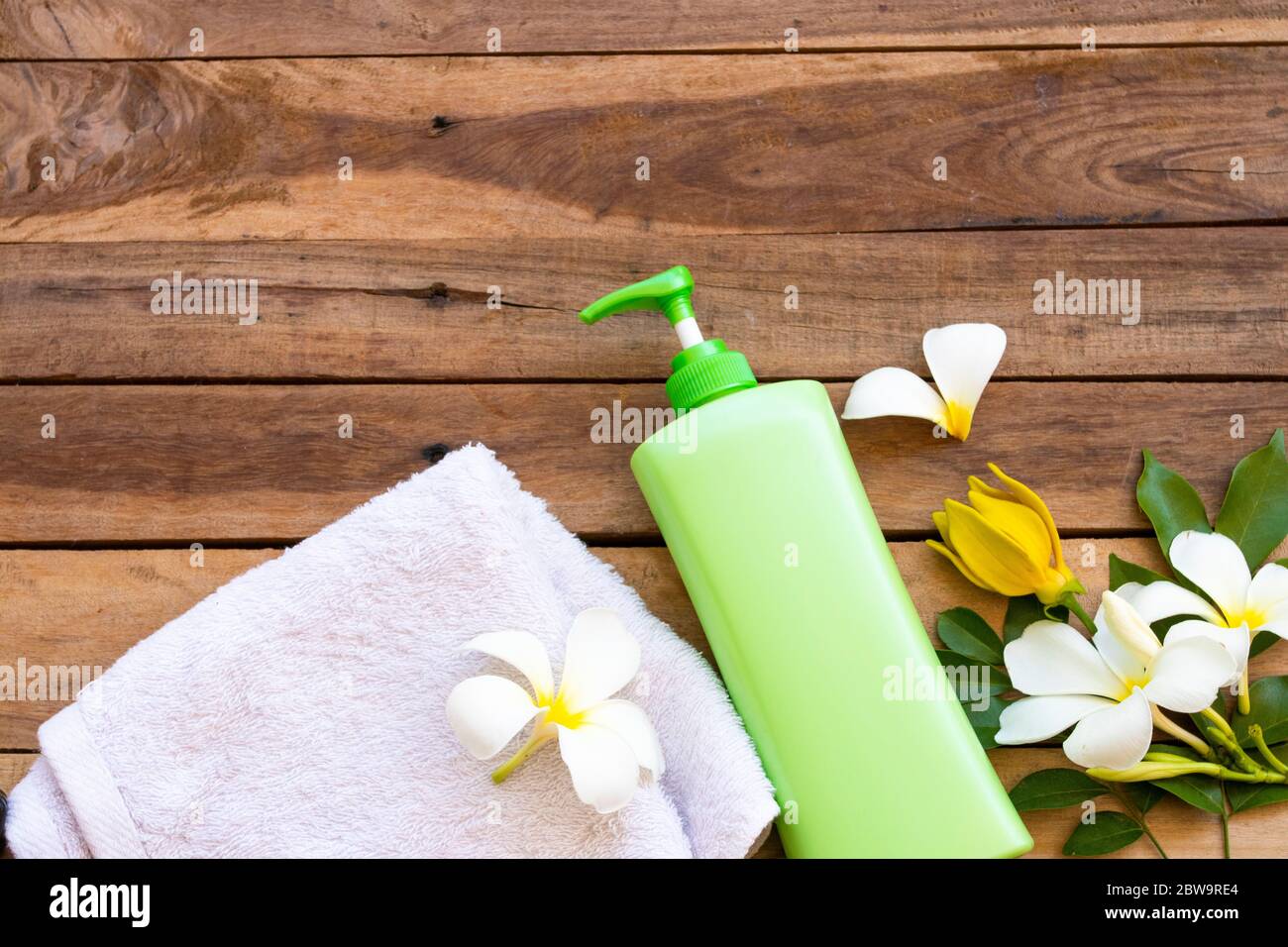 natural herbal liquid soap health care for body skin with terry cloth ,flower frangipani ,ylang ylang arrangement flat lay style on background wooden Stock Photo