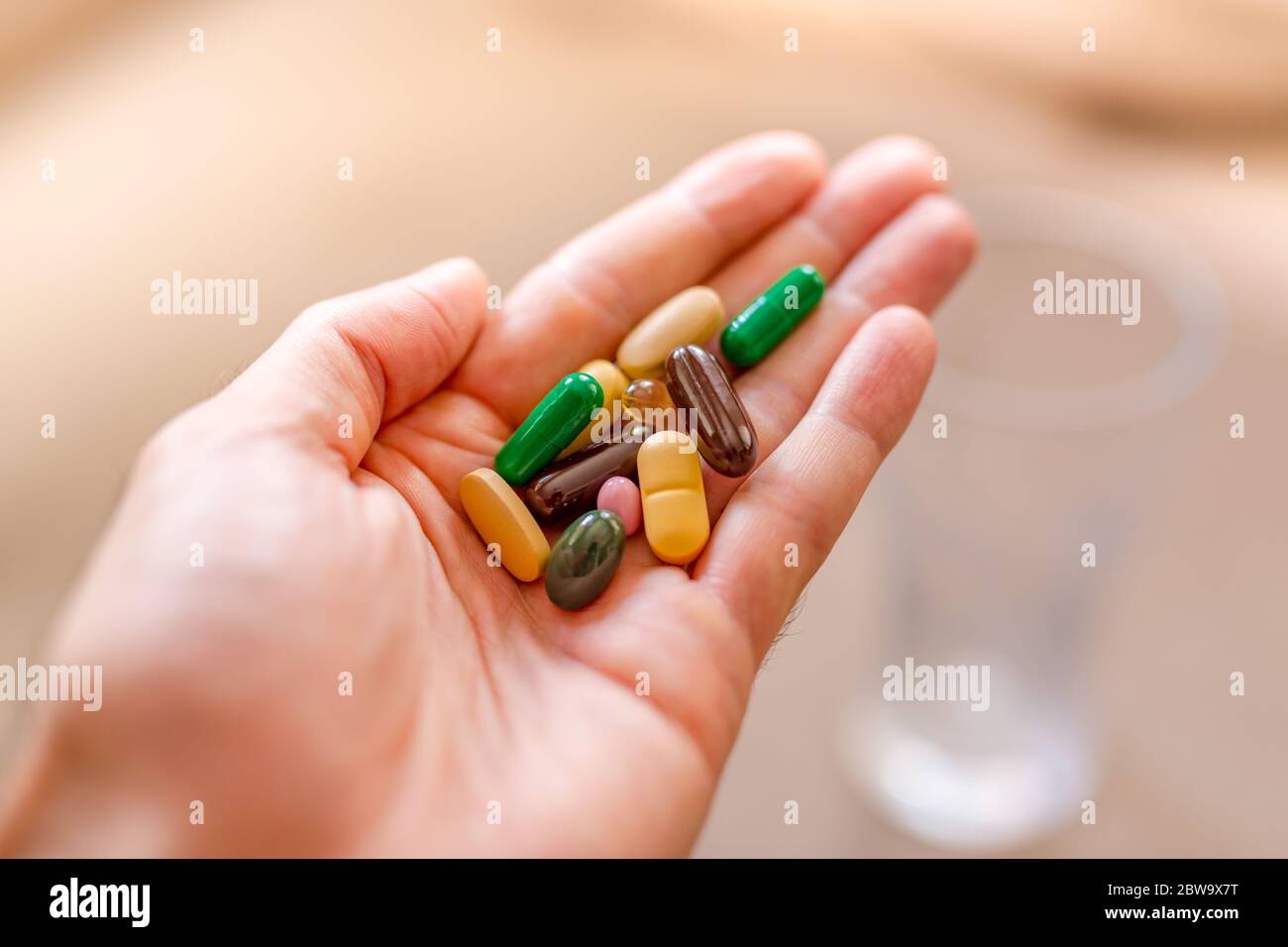Immune system boost with vitamins. Colorful pharmaceutical medicine pills, narcotic drugs and vitamin in capsules on palm. Copy space for text. Stock Photo