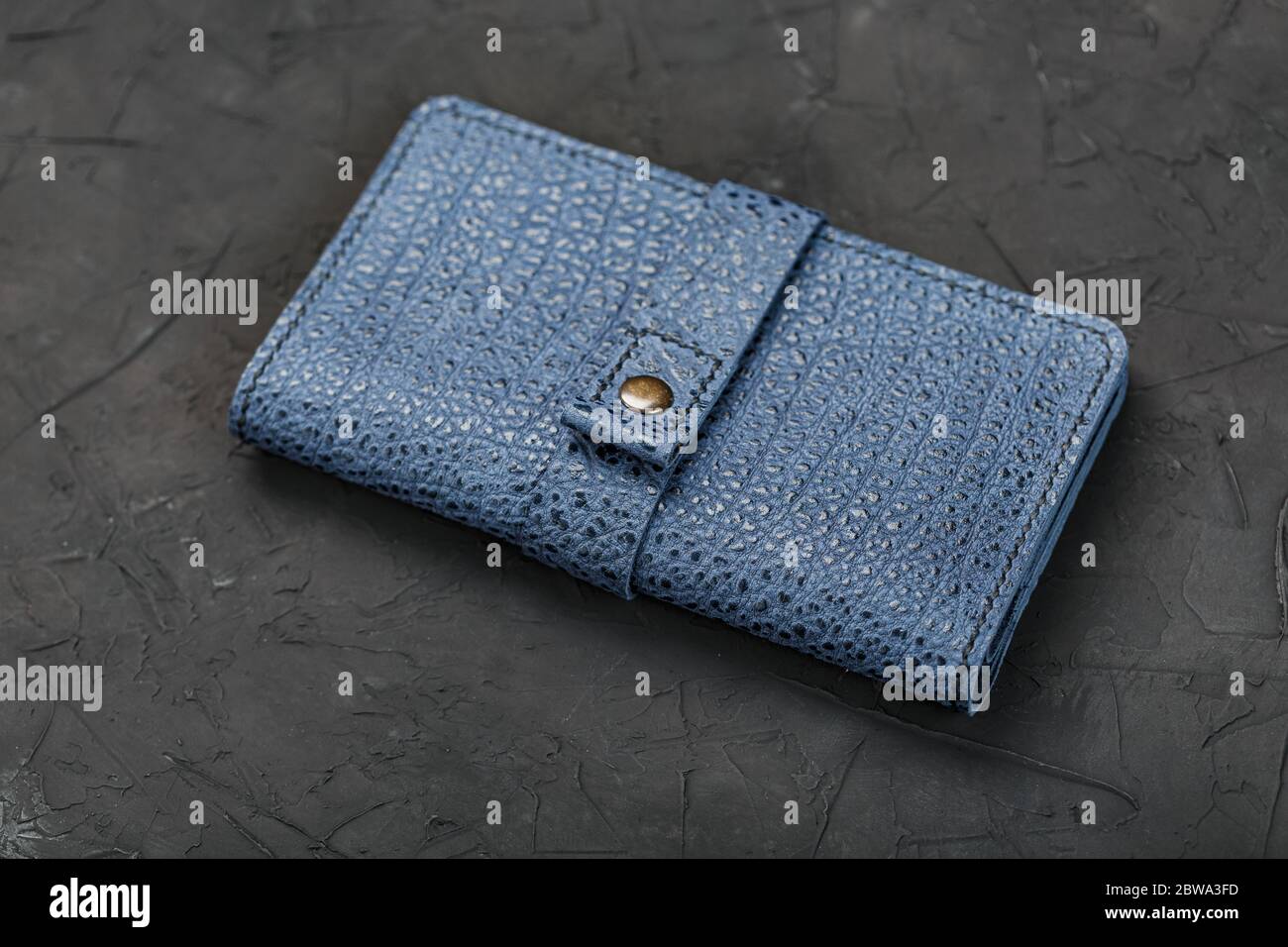 Blue leather wallet on a black textured background. Stock Photo