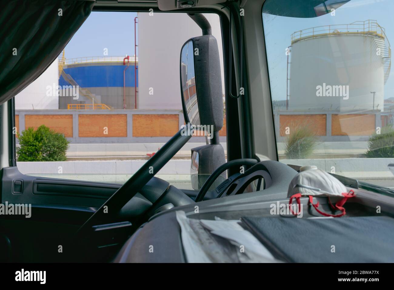 Truck interior, dashboard with a mask and fuel storage tanks in the background Stock Photo