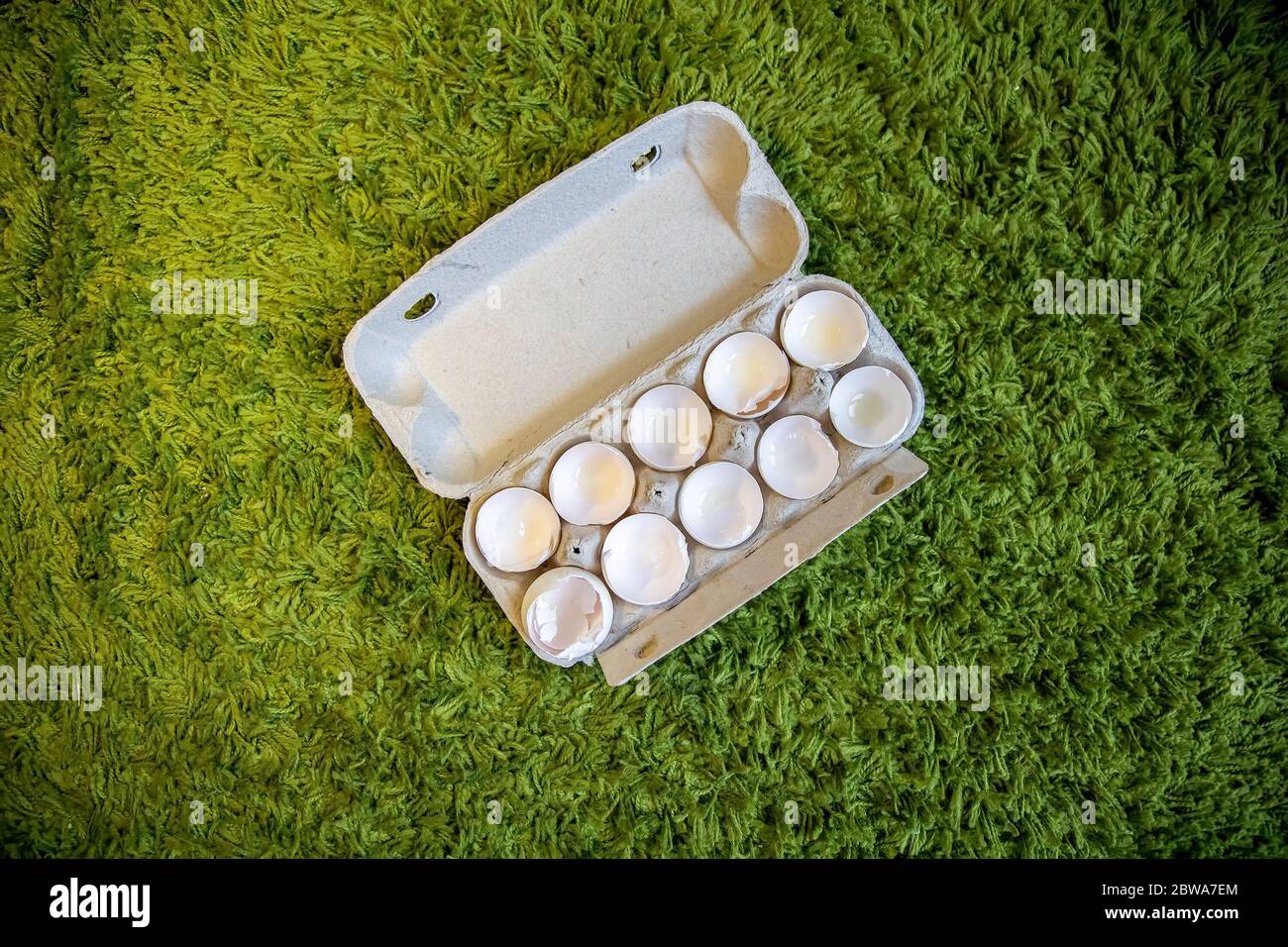 10 broken empty egg shells lie in a box on artificial grass. top view, close-up Stock Photo