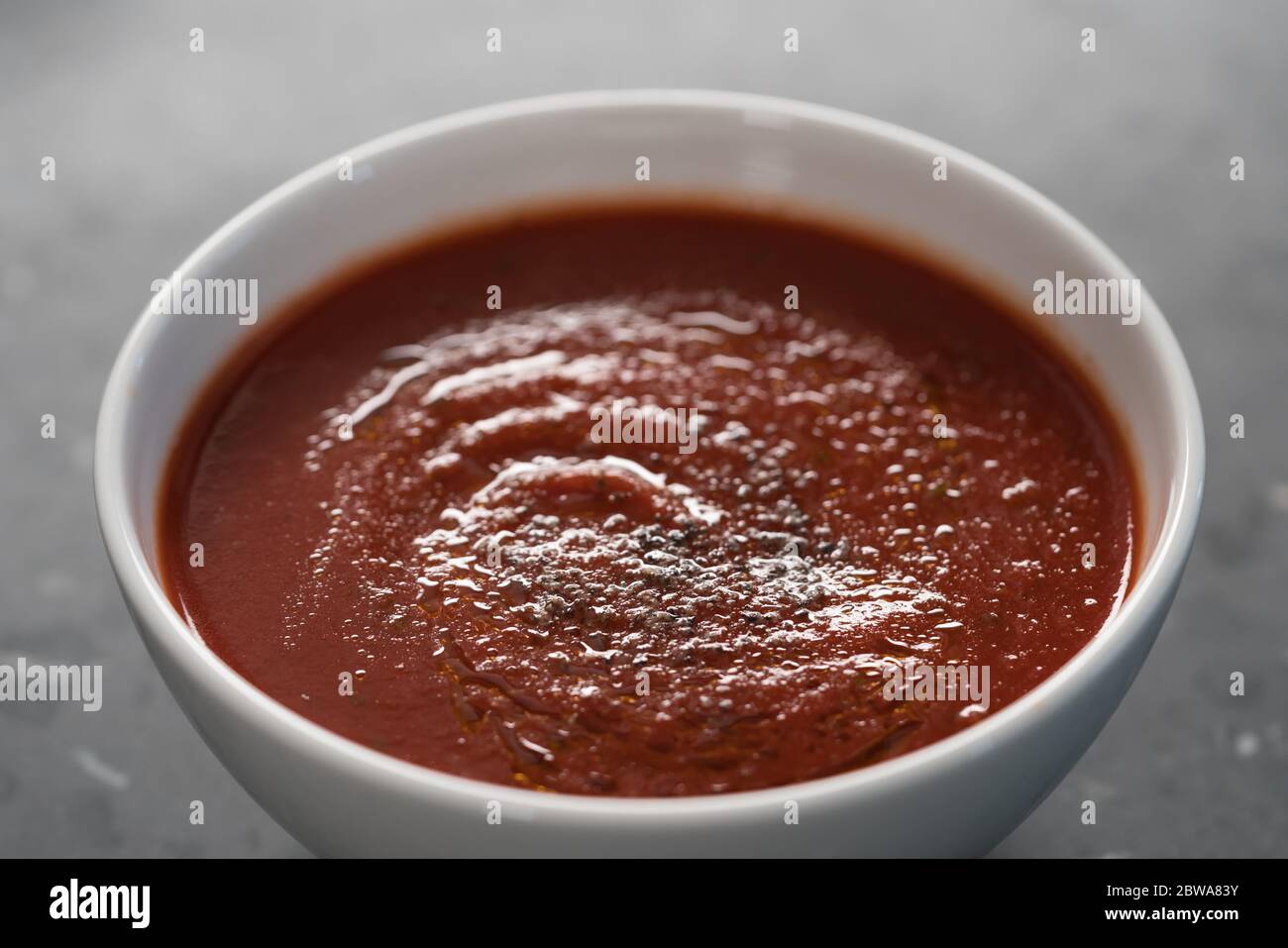 spicy tomato soup puree in white bowl on concrete background Stock Photo