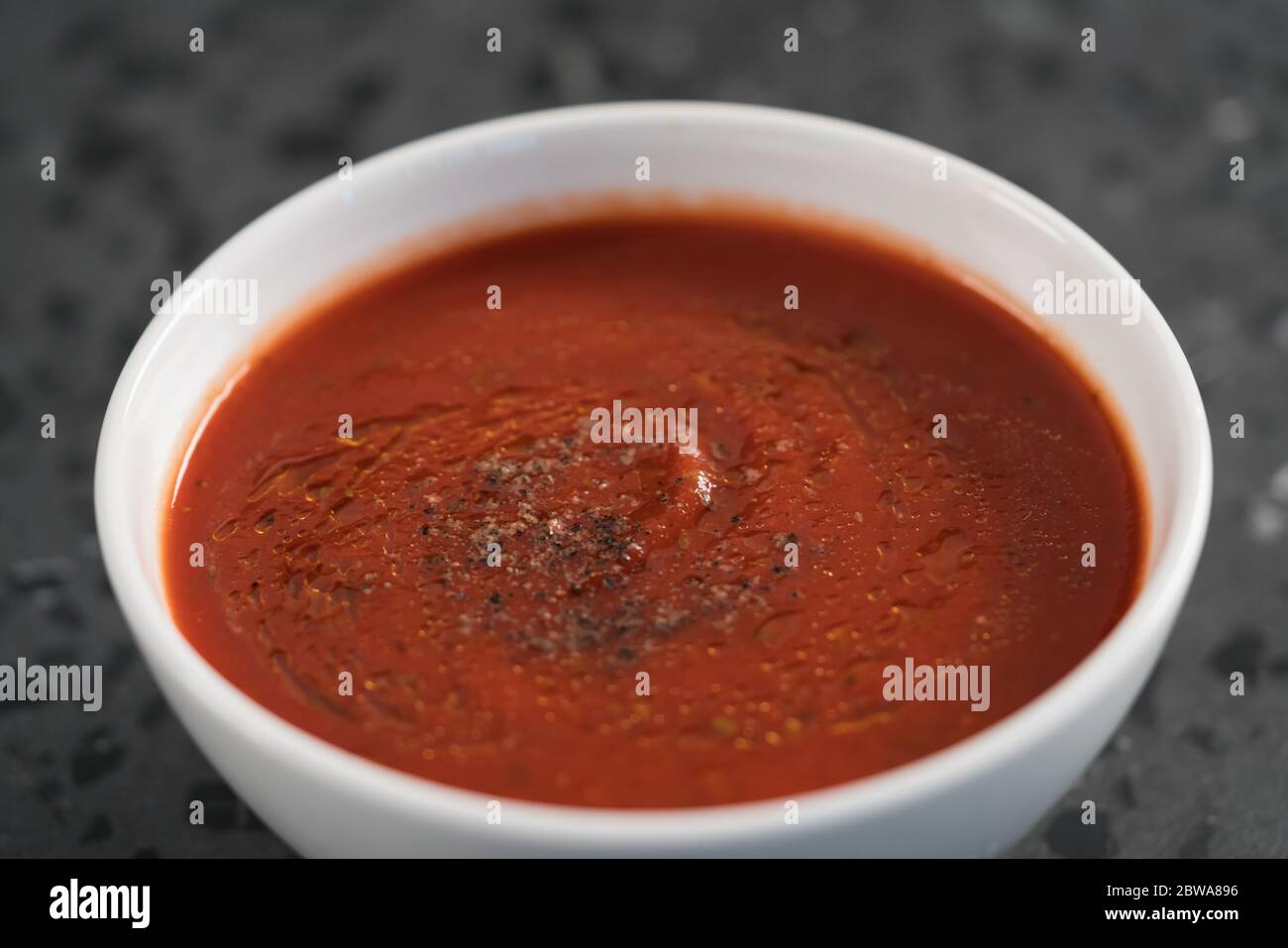 spicy tomato soup puree in white bowl on concrete background Stock Photo