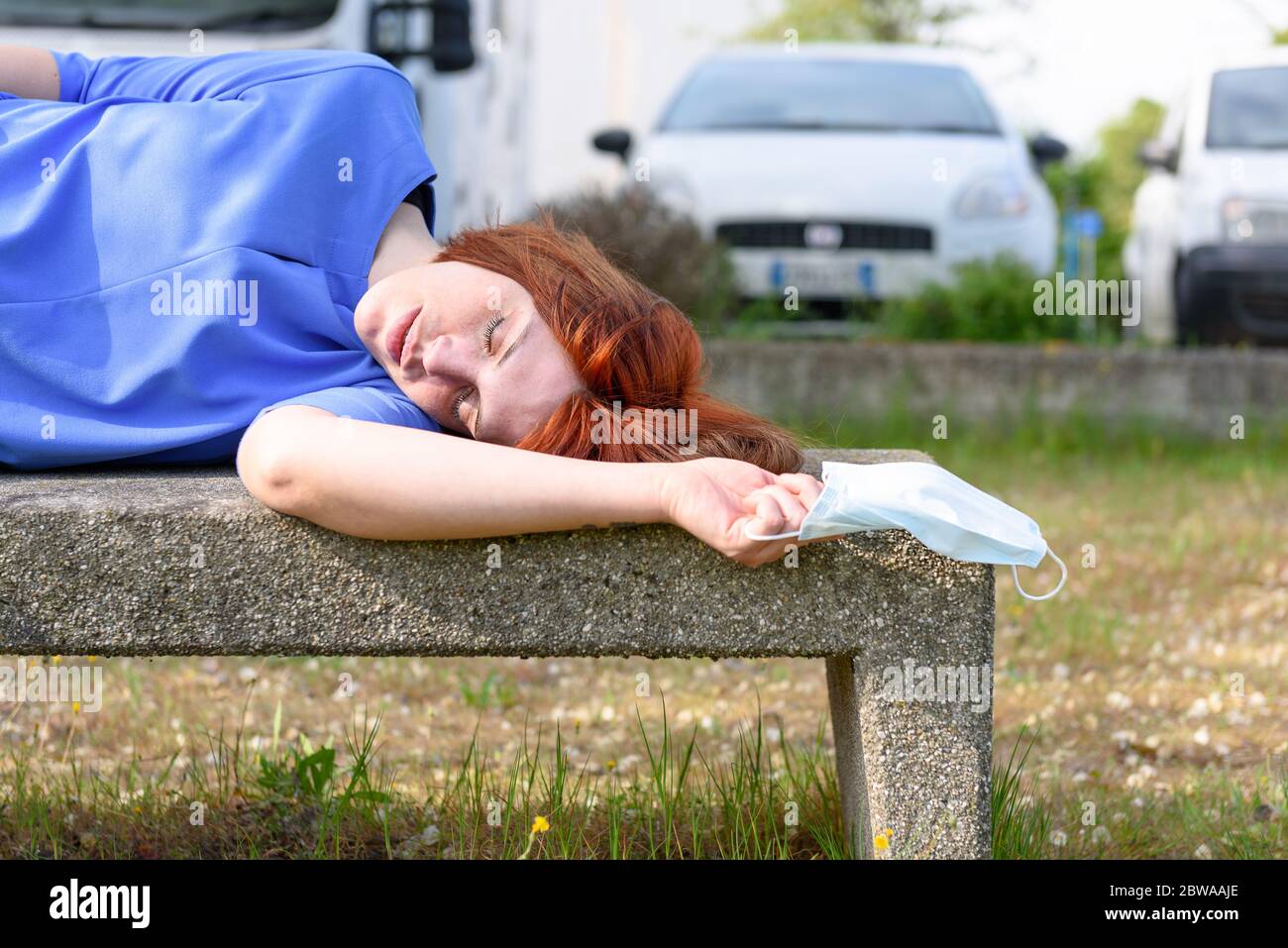 Dead / sleeping / weak girl on the bench with surgical mask in her hand