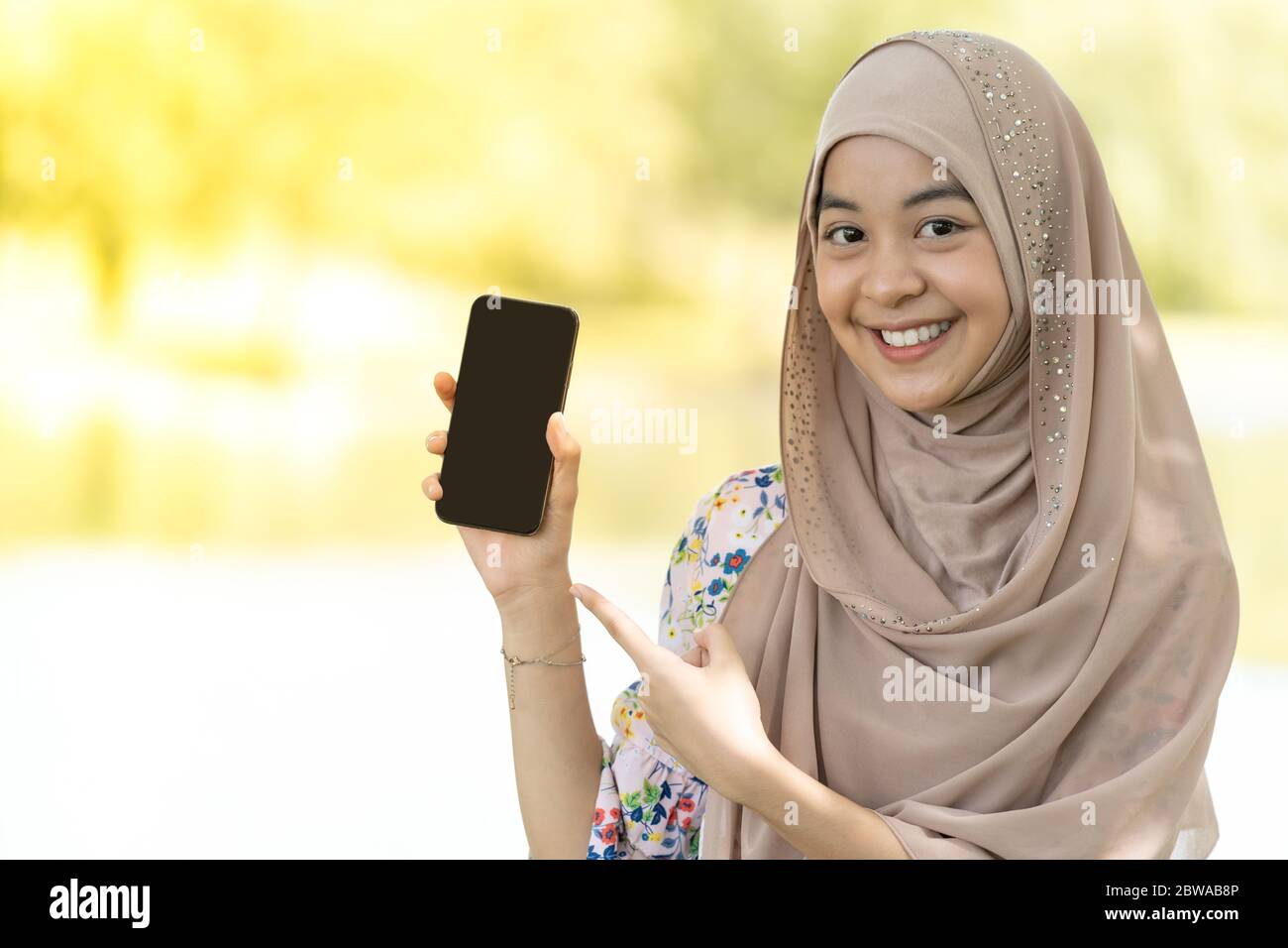 Portrait of good-looking Happy young teenager Muslim islamic asian university girl holding mobile phone Stock Photo