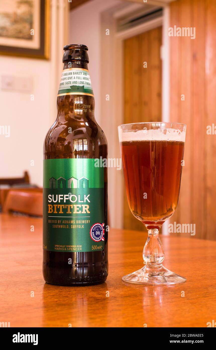 A brown glass bottle of Suffolk Bitter ale and a glass full of a popular beverage in UK Stock Photo