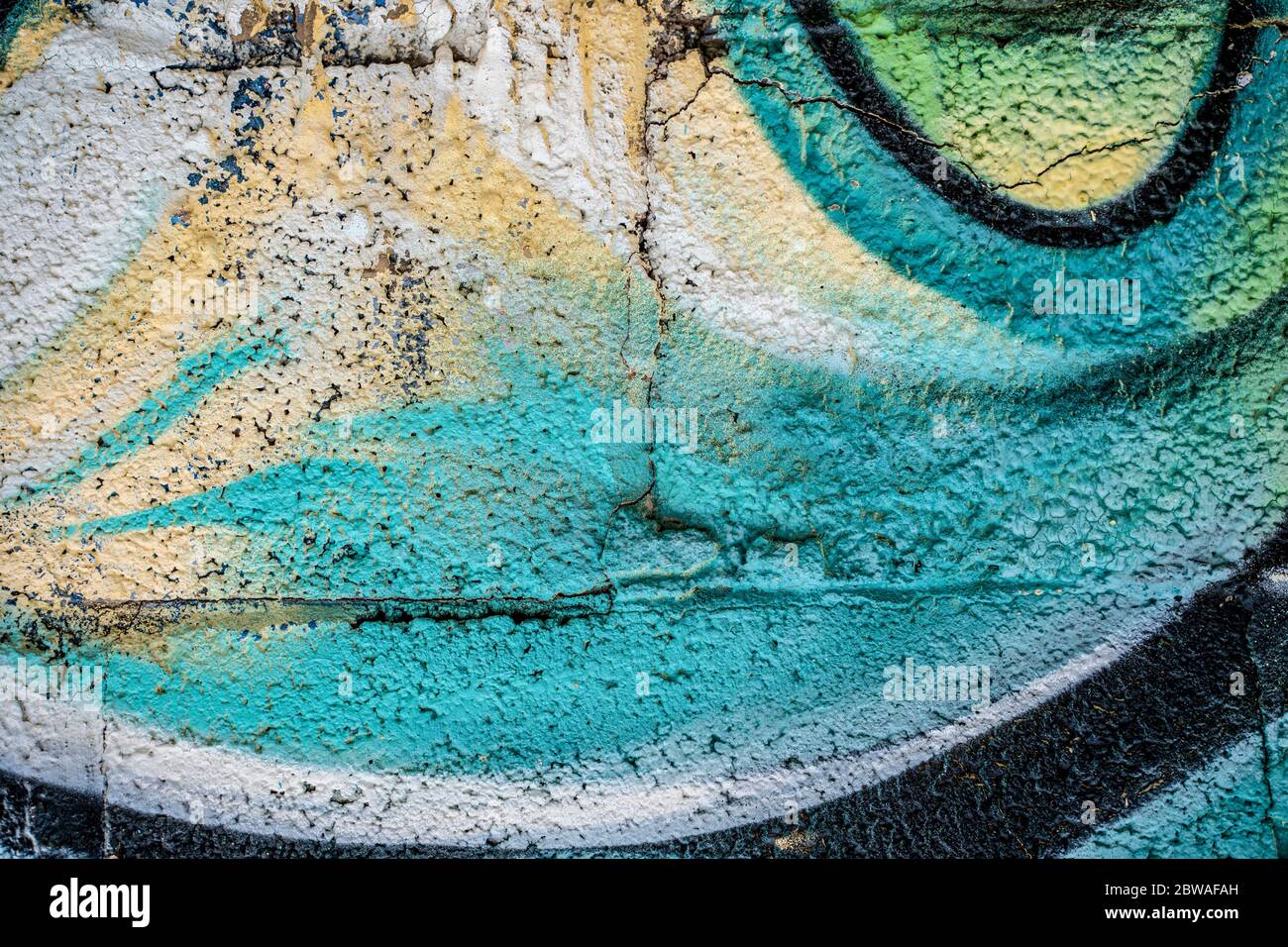 Graffiti close-up on concrete block wall texture. Street art background. Green, yellow and white. Stock Photo