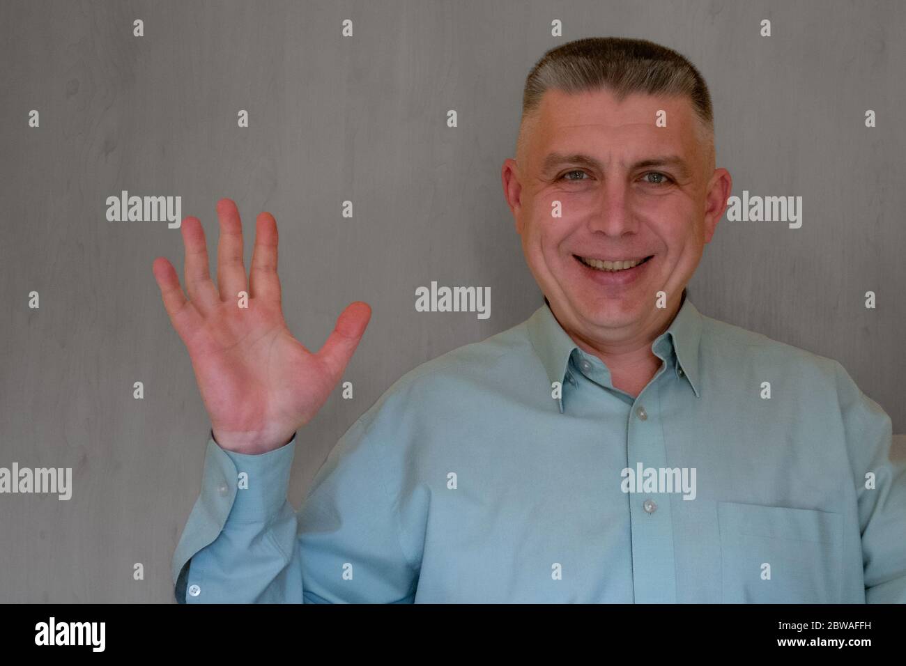 Middle aged man portrait. Open palm gesture of 40 years man looking at  camera and smiling. Blue business shirt is dressed. Happy face and positive  emo Stock Photo - Alamy