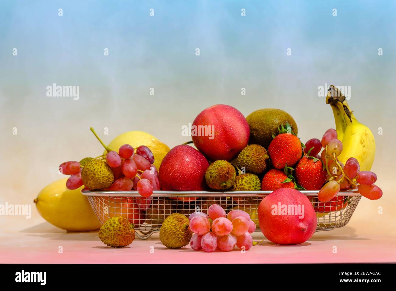 Assortment of exotic fruits in metal basket isolated on light background Stock Photo