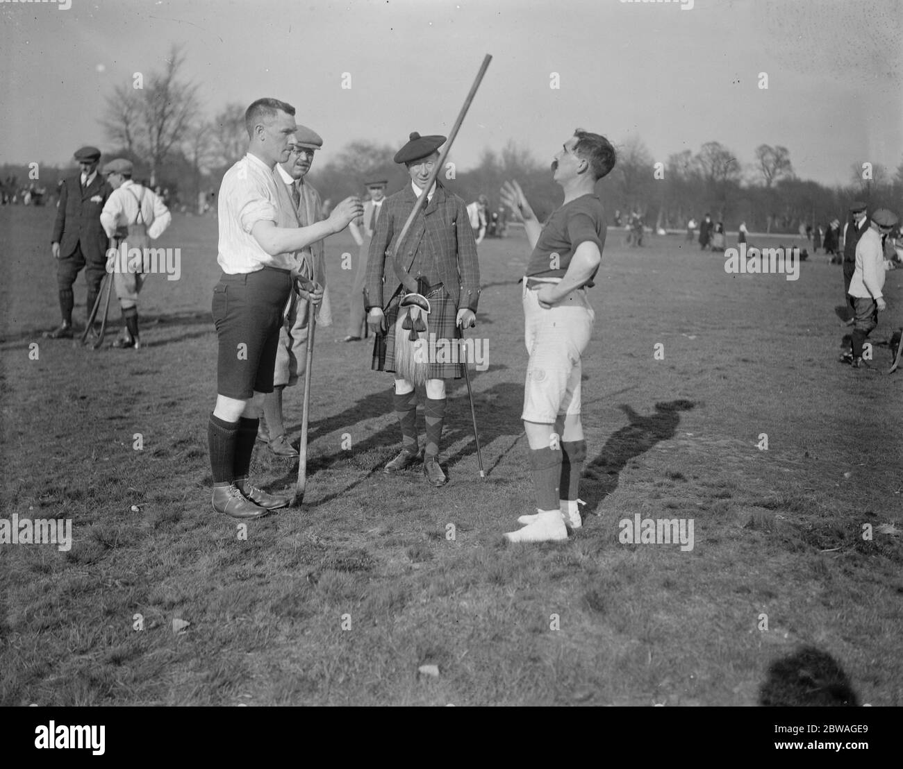 Shinty Match on Wimbeldon Common . The London Camanachd Club hold their annual shinty match at the Windmill , Wimbeldon Common . A Corbert and Alexander Macewan ' draw ' for sides . Mr D Henderson ( in Highland costume ) acted as starter . 28 March 1921 Stock Photo
