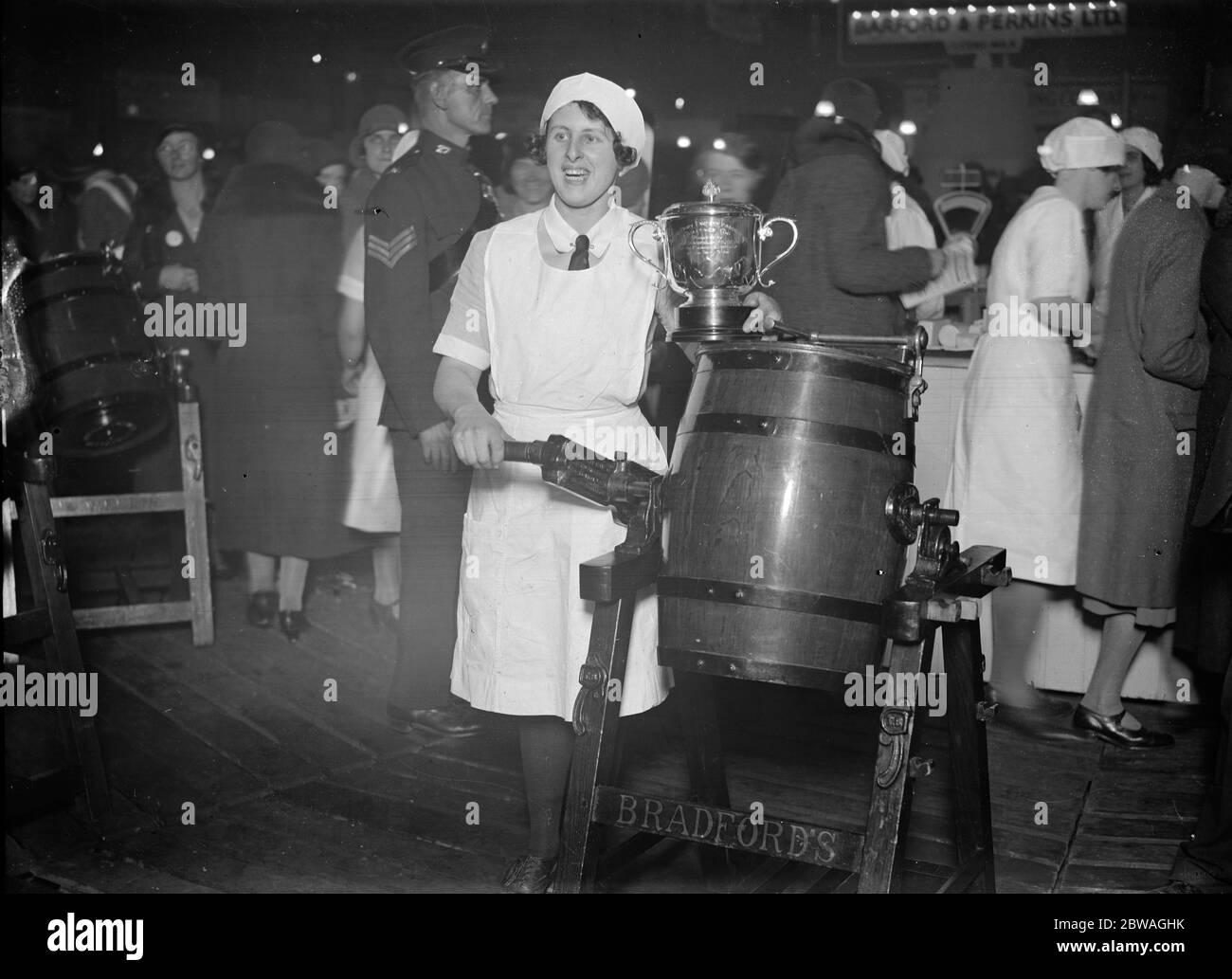 Miss Rosa Hancock , Champion Dairymaid at the Royal Agricultural Halls , Islington , London , with her butter churn and her trophy . 1931 Stock Photo