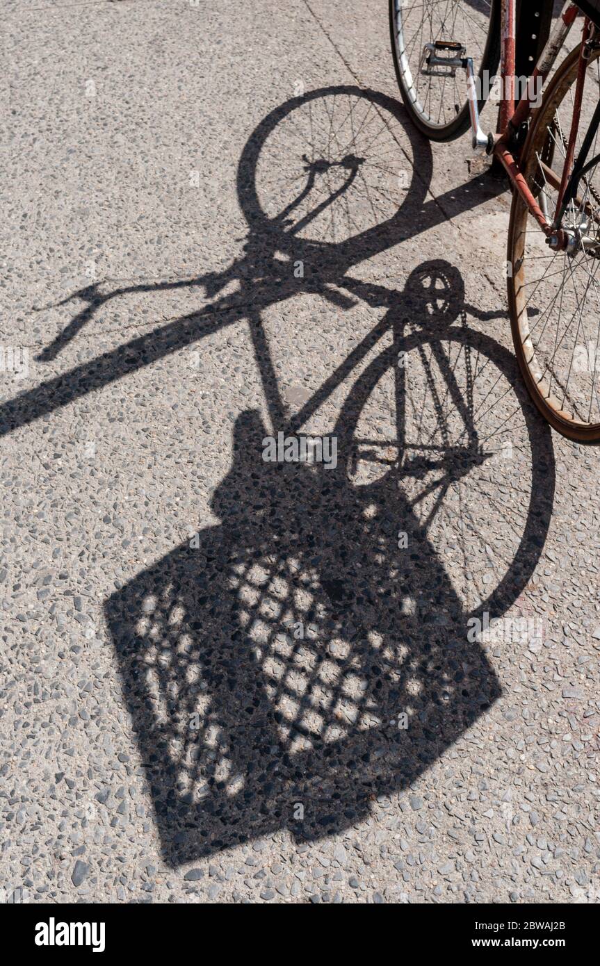 Shadow of a bicycle locked to a pole on a sidewalk in Brooklyn, New York, USA. Stock Photo