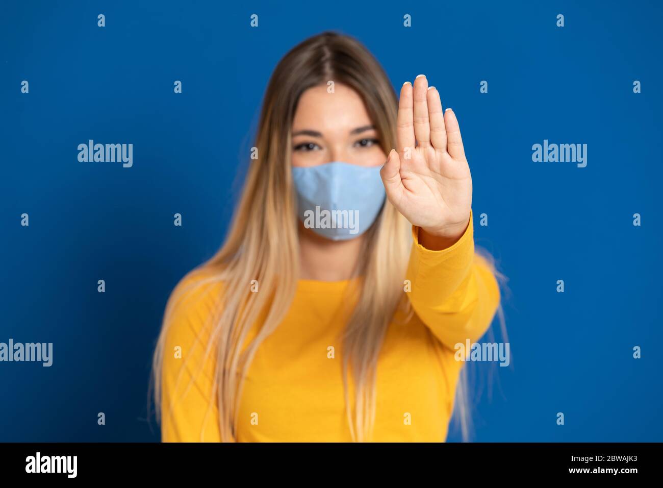 Blonde girl wearing a face mask on a blue background Stock Photo - Alamy