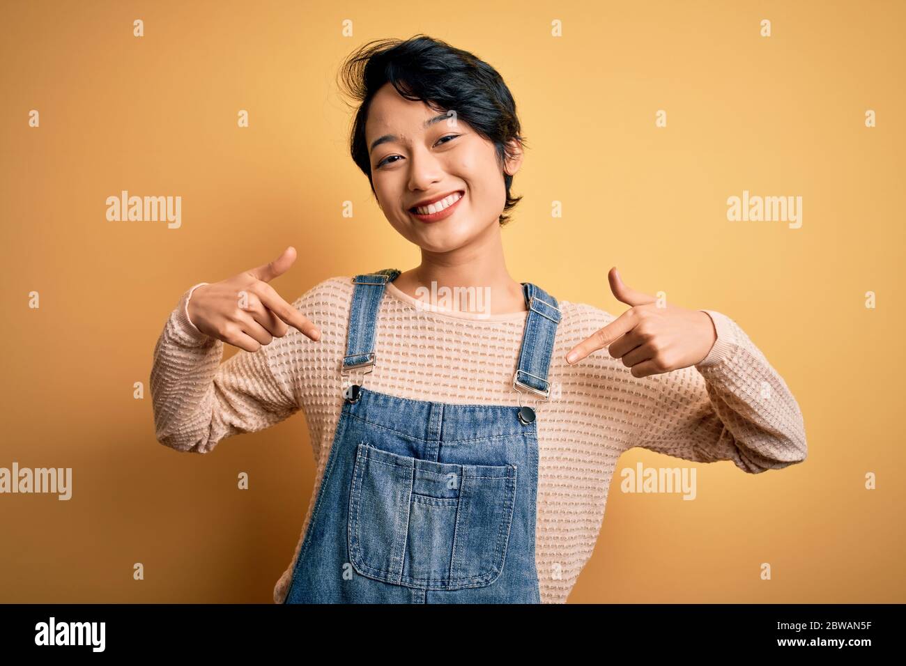 Young beautiful asian girl wearing casual denim overalls over isolated ...