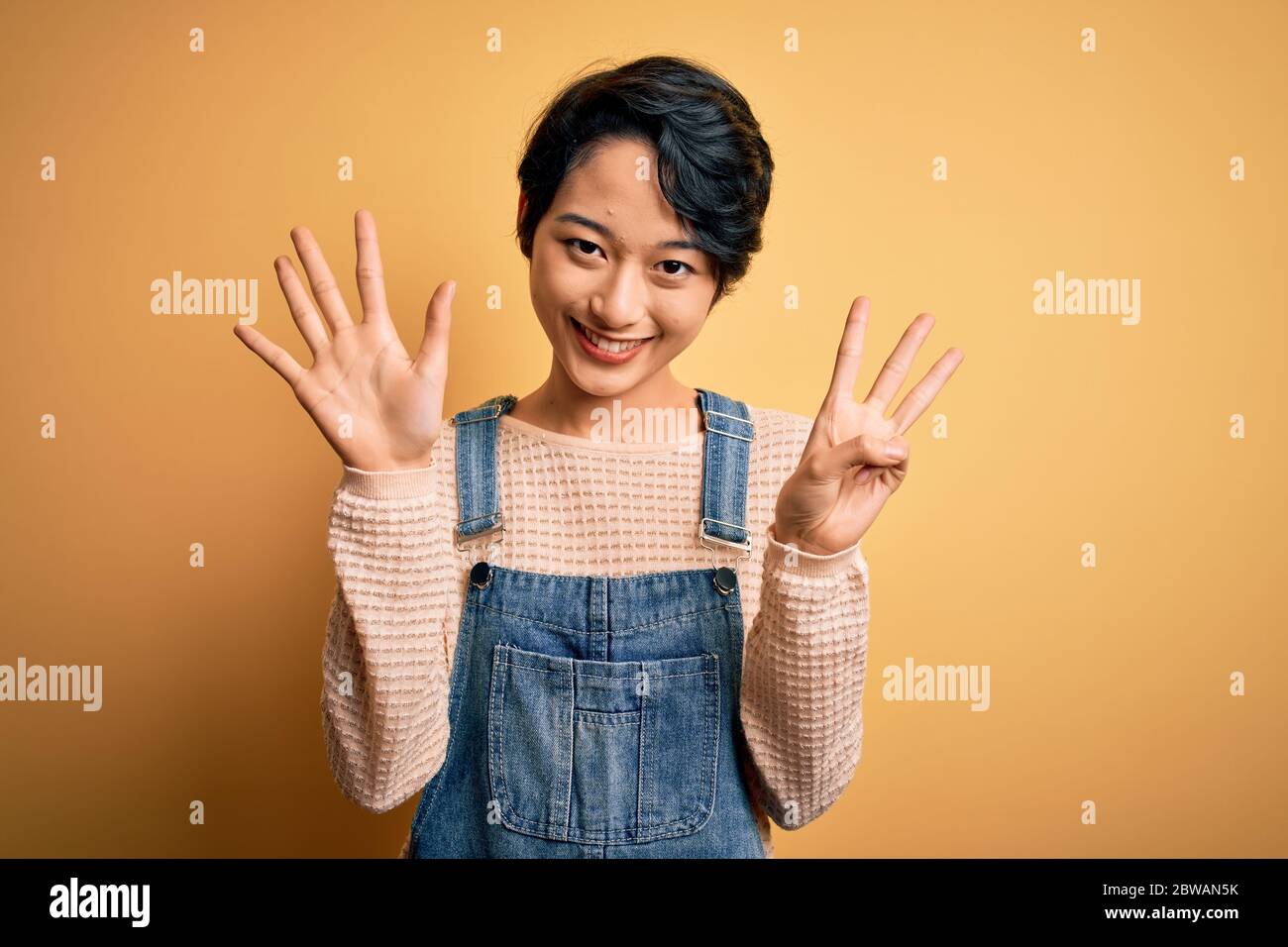Young beautiful asian girl wearing casual denim overalls over isolated ...